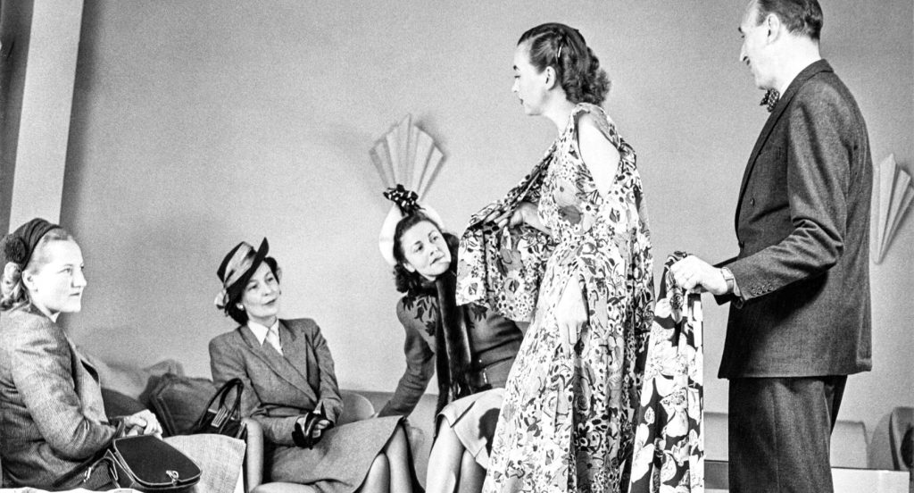 Chefskreatören Pelle Lundgren och en mannekäng visar tyger och modeller för kunderna i visningssalongen på NK:s Franska damskrädderi i Stockholm.